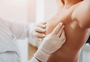 Doctor get examining breast of young woman